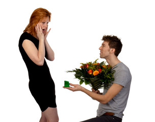 Young man offers his surprised girlfriend a large bouquet of flo