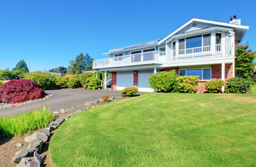 Two story American house with large deck and two garages.