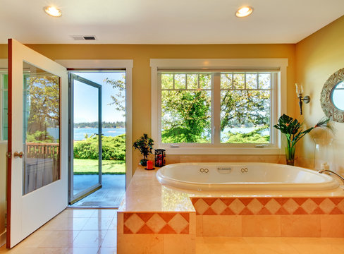 Yellow bathroom with lake view and large tub.