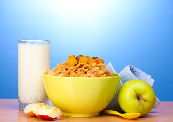 tasty cornflakes in green bowl, apples and glass of milk
