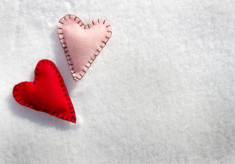 Two stitched hearts on snow