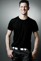 Young man in black t-shirt on gray background.