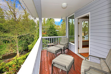 Balcony with outdoor furniture and view of woods and river.