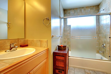 Bathroom interior with stone tile, wood cabinet and tub.