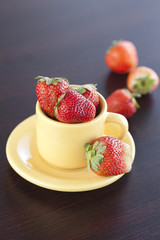 strawberries and a cup with saucer on a wooden table