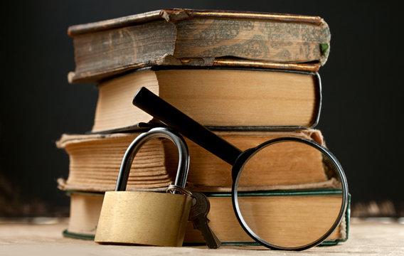 Old books with keylock and magnifying glass