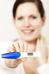 Positive pregnancy test with smiling woman in the background