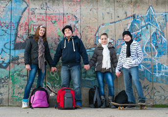 Fototapeta na wymiar Teenage boys and girls with school bags holding hands
