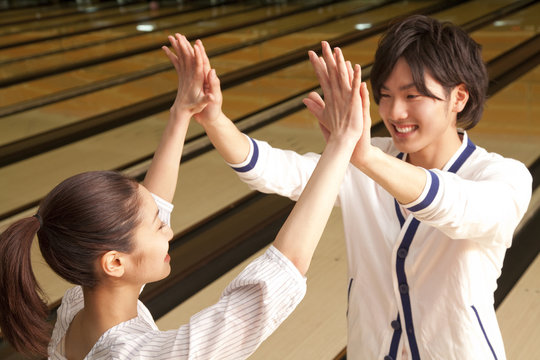 ボウリング場でハイタッチをする男女