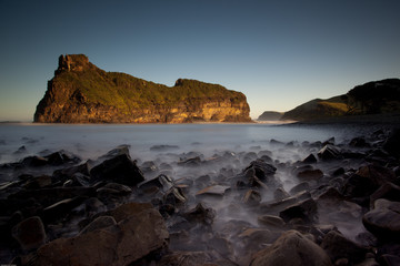 Fototapeta na wymiar long exposure image of island and black rocks with blurred ocean