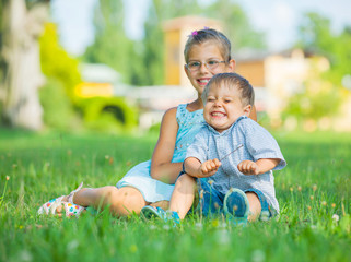 Little boy and his sister in the summer park