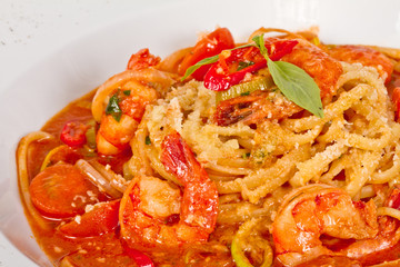 A plate of linguini with sauteed shrimp, tomato, chili  and oliv