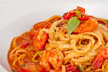 A plate of linguini with sauteed shrimp, tomato, chili  and oliv