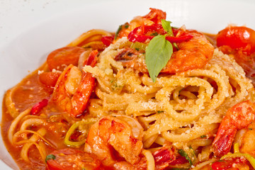 A plate of linguini with sauteed shrimp, tomato, chili  and oliv