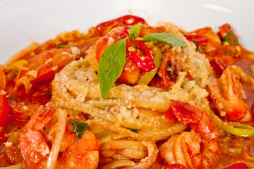 A plate of linguini with sauteed shrimp, tomato, chili  and oliv