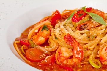 A plate of linguini with sauteed shrimp, tomato, chili  and oliv