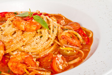 A plate of linguini with sauteed shrimp, tomato, chili  and oliv