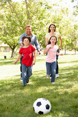 Family playing football in park