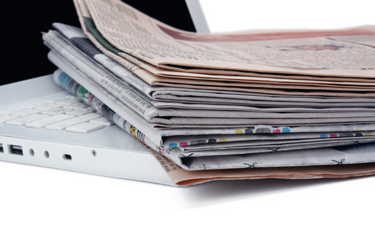 stack of newspaper next to a laptop