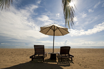 Two empty chairs and a sunshade at a beach in Bali