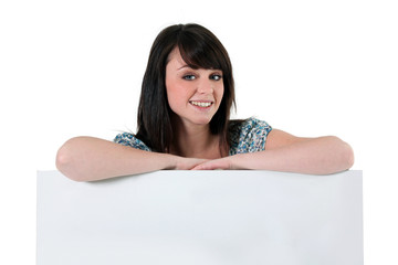 Young woman leaning on a blank sign