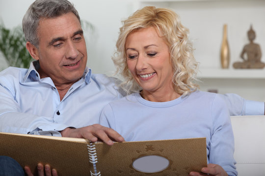 Middle-aged couple looking through photo-album