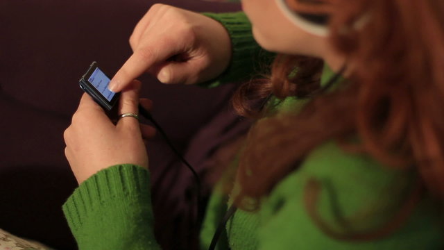 Redheaded woman uses an mp3 player