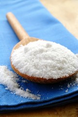 salt in a brown wooden spoon and a blue cloth