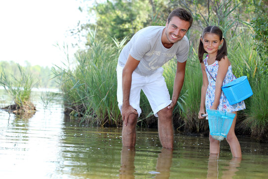 a daughter and her father fishing in a river