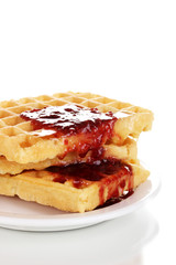 Tasty waffles with jam on plate close-up isolated on white
