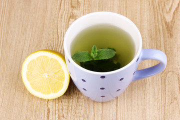 Mint tea with mint leaf and lemon on wooden background