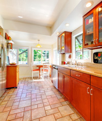 Charming cherry wood kitchen with tile floor.