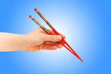 Hand holding choipsticks on gradient