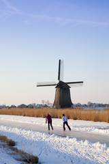 Windmill in winter time with snow, ice and blue sky