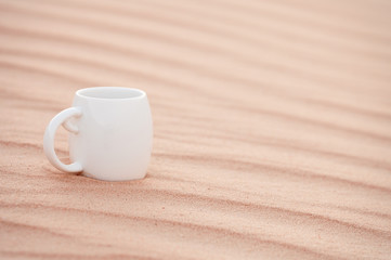 white coffee cup in sahara sand dune,  Grand Sand Sea, shallow d