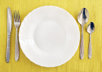 White empty plate, fork, spoon and knife
