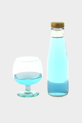 Blue beverage drinking glass and bottle on gray background.