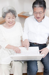 ノートパソコンを見る笑顔のシニアカップル