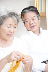 編み物をするシニア女性と笑顔のシニア男性