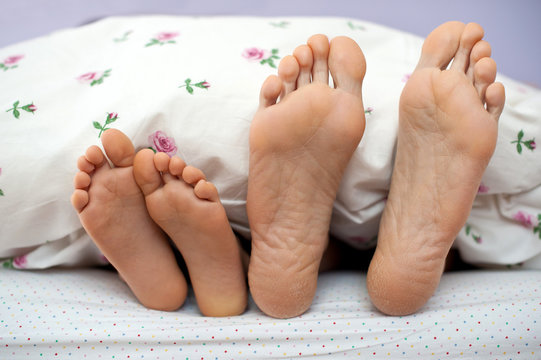 Mother and son bare feet in bed.