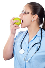 Young female doctor eating apple isolated on white