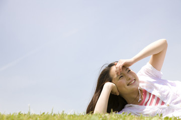 芝生に寝転がり空を眺める女性