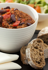 Hot and spicy minced meat chili with fresh bread and salad