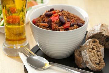 Hot and spicy minced meat chili with fresh bread and cold beer