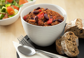 Hot and spicy minced meat chili with fresh bread and salad