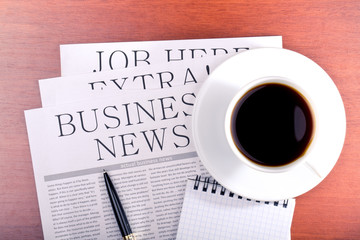 Business newspaper, notebook and cup of coffee