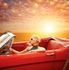 Woman driving retro car against beautiful sky.