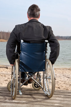 Mann sitzt im Rollstuhl in der Natur