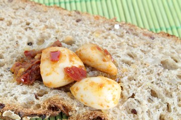 spicchi d'aglio sott'olio su fetta di pane ai cereali