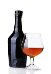 Glass of brandy and bottle isolated on white